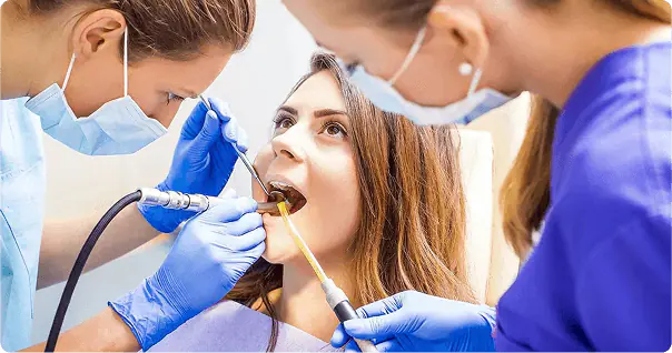 Dentist and assistant cleaning a patient's teeth